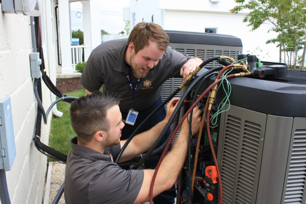 two smo energy technicians working on an ac